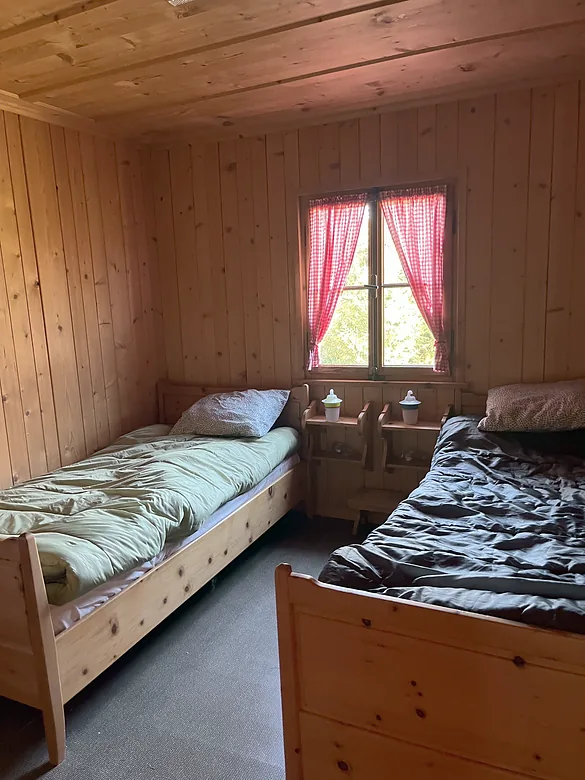 Schlafzimmer aus Holz mit zwei Betten und einem Fenster